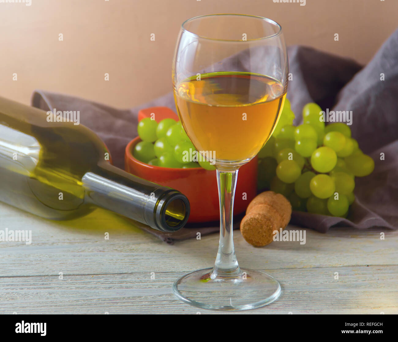 Bicchiere da vino, uva verde su lastra sul tavolo Foto Stock