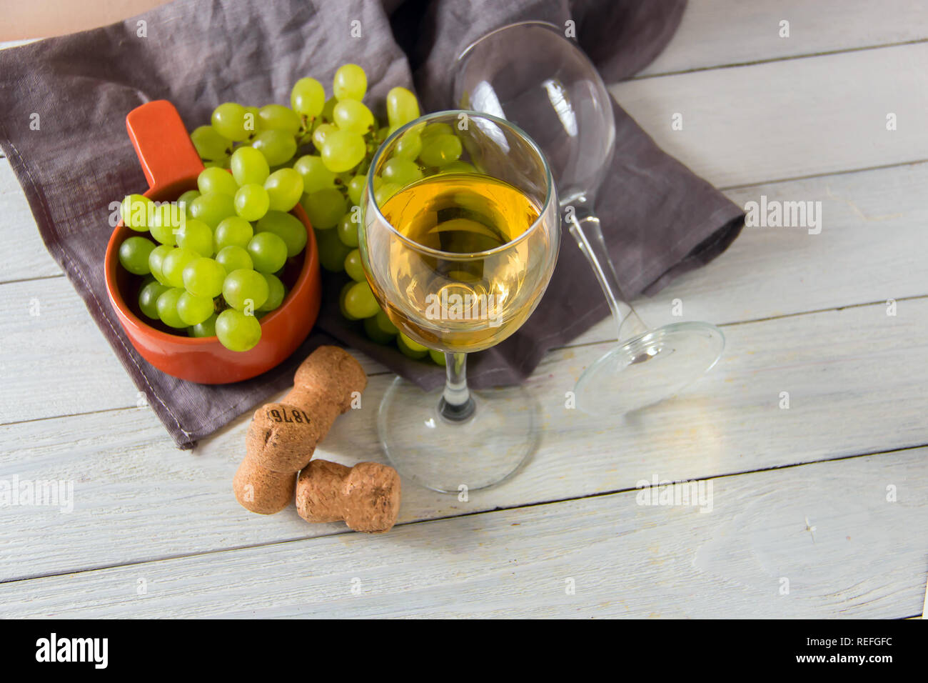 Bicchiere da vino, uva verde su lastra sul tavolo Foto Stock