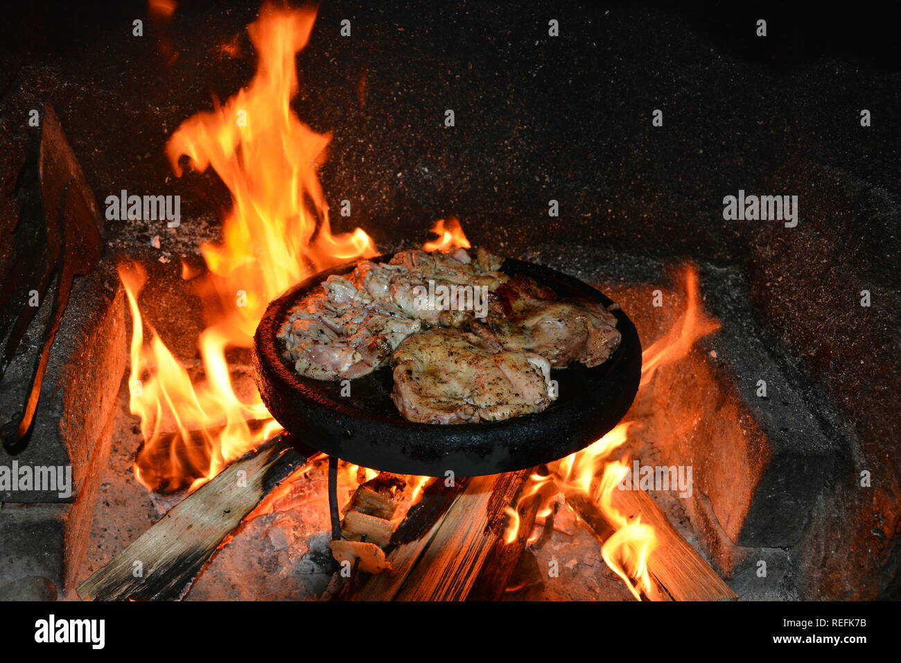 La cottura di pasto di pollo in piastra ceramica sul camino Foto Stock