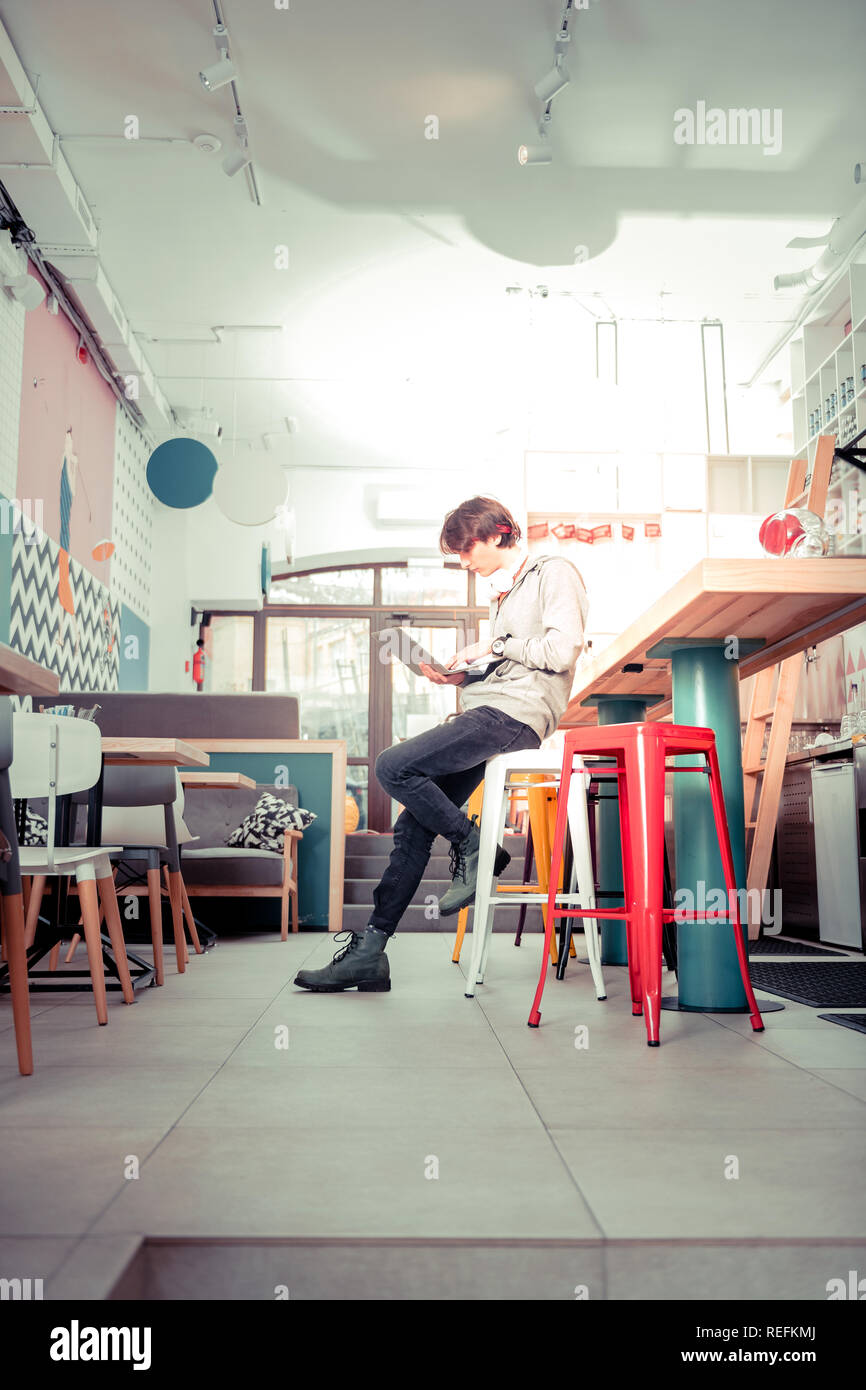 Adolescente utilizzando la connessione wi-fi gratuita nella caffetteria Foto Stock