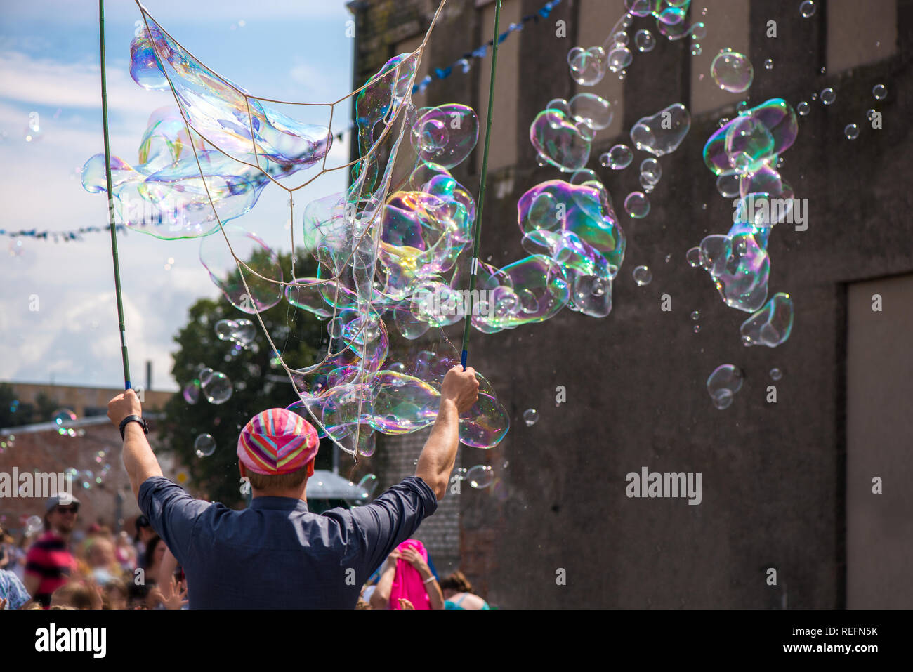 Un clown freelance soffiando centinaia di minuscoli, piccole e grandi bolle a festival all'aperto nel centro citta'. Concetto di intrattenimento, compleanni. I bambini aventi Foto Stock