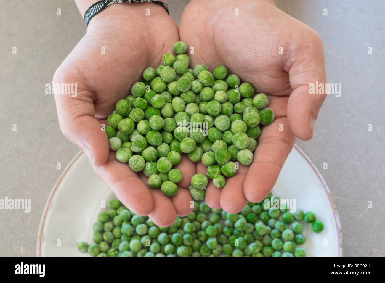 Mani di piselli verdi sullo sfondo di una piastra non focalizzato. Vista superiore Foto Stock