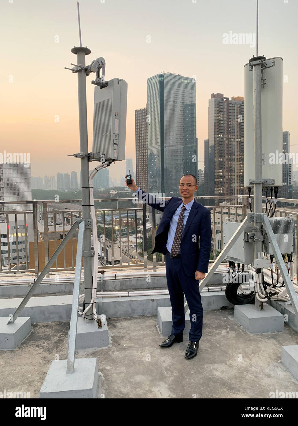 Shenzhen, Cina. Xxi gen, 2019. Un dipendente del cinese operatore Mobile China Telecom mostra una stazione di base da Huawei per il nuovo 5G network (l) e sorge su un tetto di un edificio alto in Nanshan District accanto ad un convenzionale 4G stazione (r). In Shenzhen, dove Huawei è anche sede, ci sono già diverse centinaia di 5G stazioni. La Cina sta spingendo avanti massicciamente con l'espansione delle nuove comunicazioni mobili standard, che trasporta i dati più velocemente e in volumi molto più grandi. Credito: Andreas Landwehr/dpa/Alamy Live News Foto Stock
