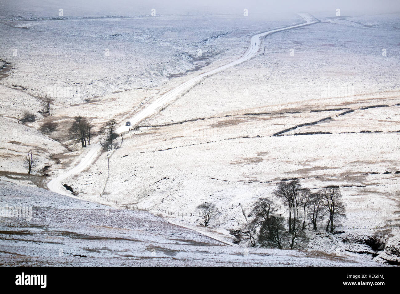 Unico stretta via strada di campagna coperta di neve sulle brughiere del Peak District appena fuori la città di Buxton Foto Stock