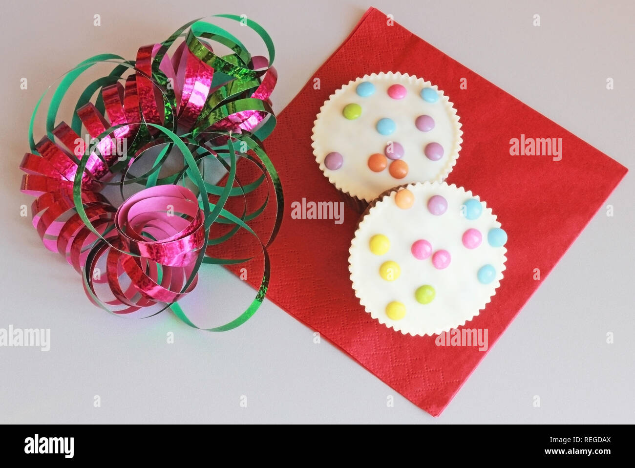 Il carnevale muffin decorati con multi colore lenticchie di cioccolato e streamers, vista dall'alto Foto Stock