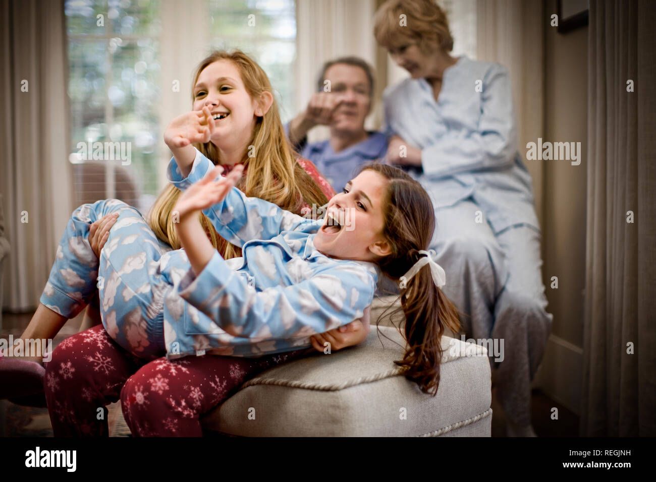 Due ragazze in riproduzione in pigiama con i loro nonni in background Foto Stock