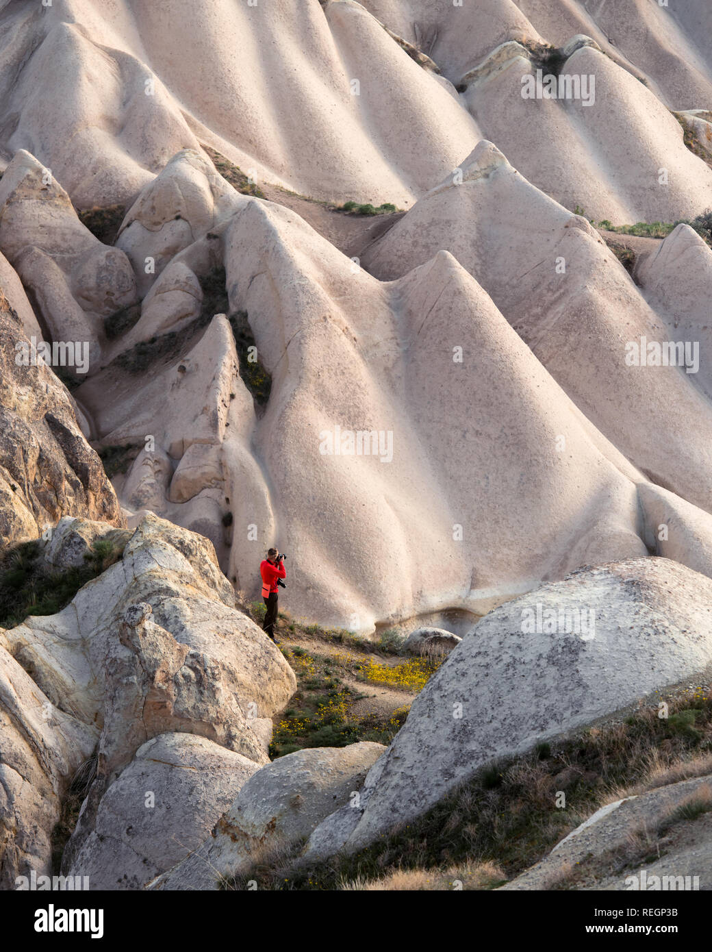 Giornata incredibile in Cappadocia montagne, Turchia. Fotografo in giacca rossa prendendo foto di meravigliose colline. Fotografia di paesaggi Foto Stock