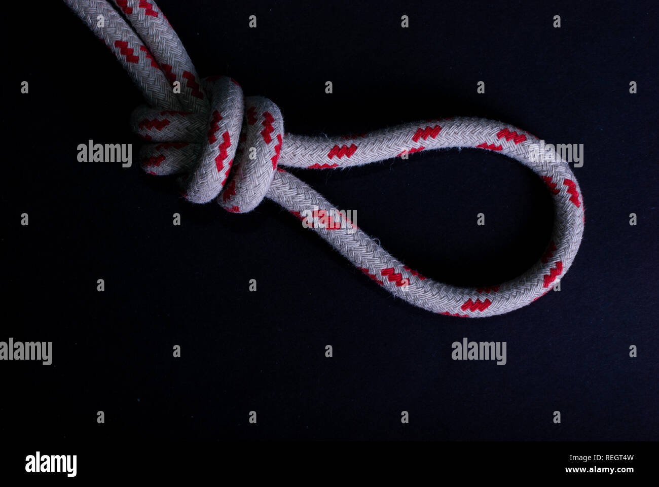 In prossimità di un nodo in un rosso e bianco corda a vela su sfondo nero Foto Stock