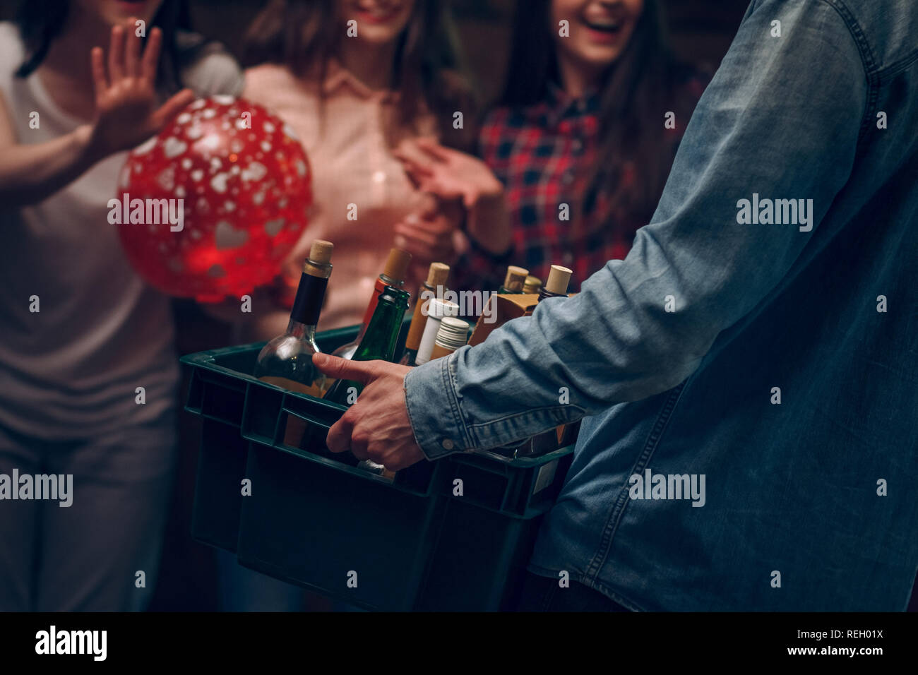 L'uomo della scatola di contenimento con bottiglie di champagne a una festa Foto Stock