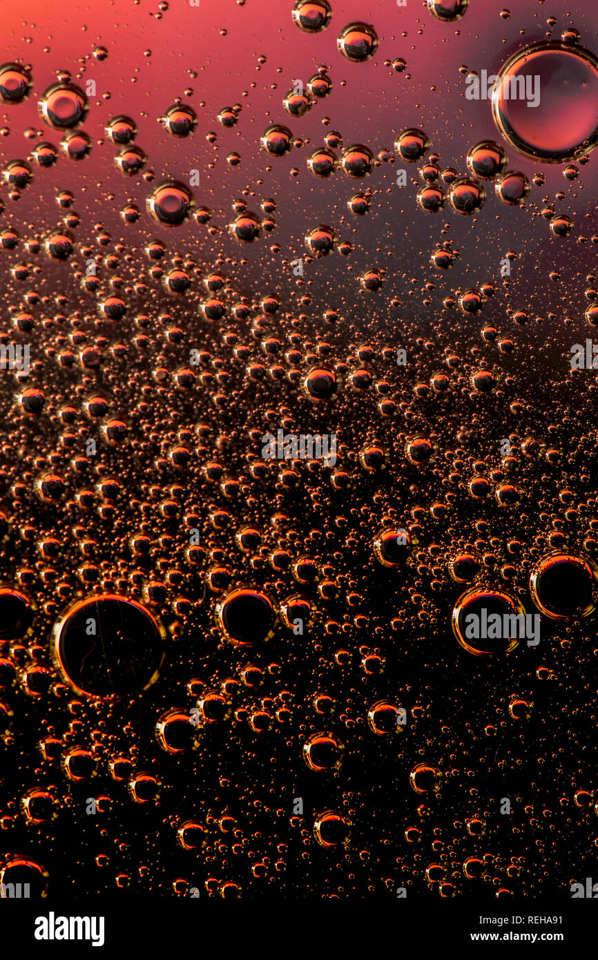 Macro shot di liquidi retroilluminato con piccole bolle su sfondo colorato. Foto Stock
