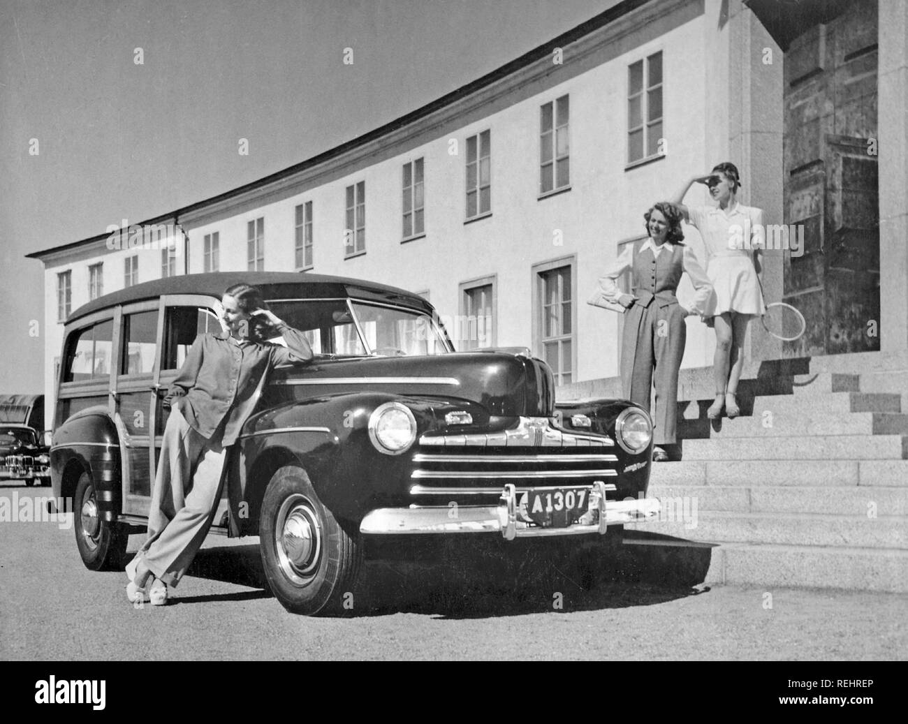 La guida nel 1940s. Una nuova vettura Ford 1946 con chassi in legno al di fuori di un edificio alla moda. Foto Stock