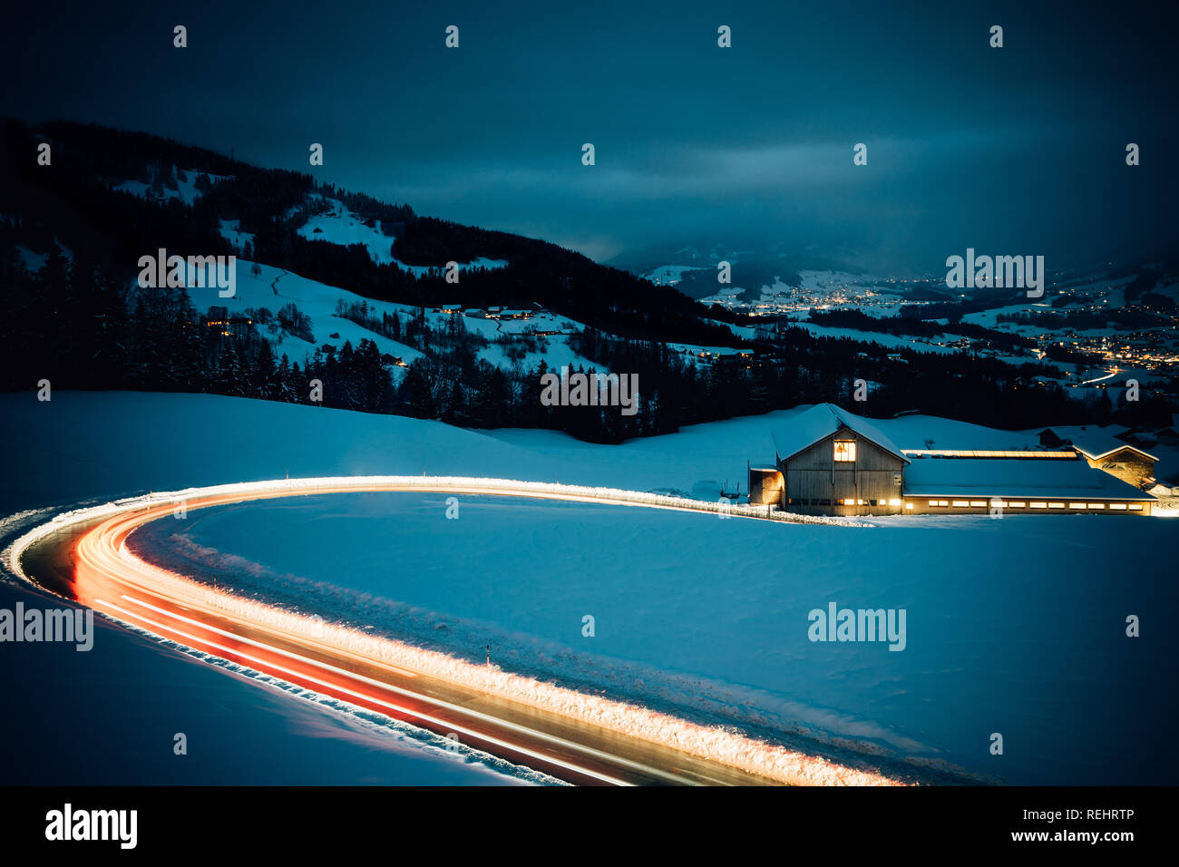 A lungo esposto notte fotografia di vetture di guidare attraverso una montagna innevata strada nelle Alpi dell'Austria. Foto Stock