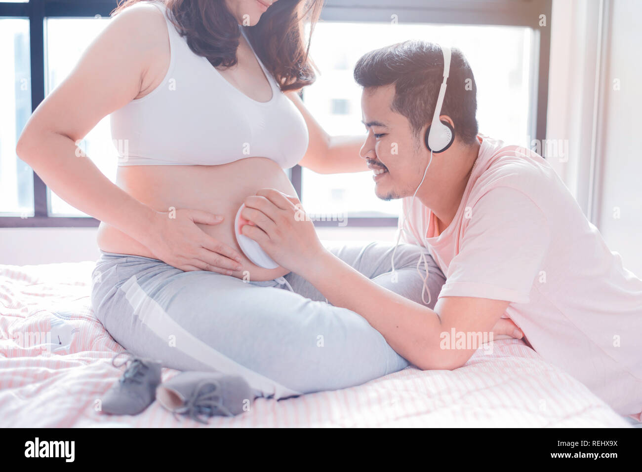 Asian donna incinta con grande pancia. Festa della mamma e la giornata internazionale delle donne. Mom rilassante con mio marito a casa Foto Stock