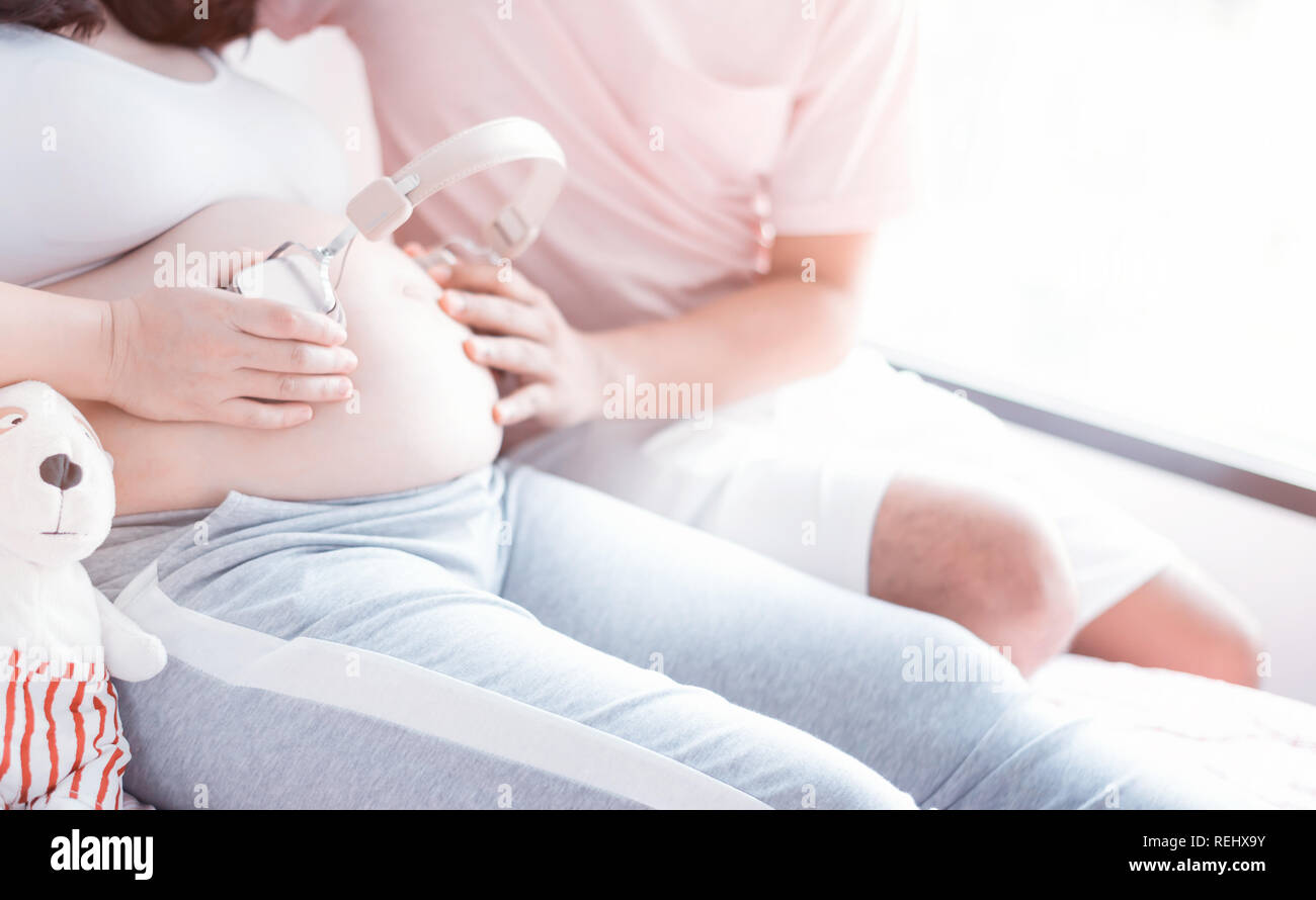 Asian donna incinta con grande pancia. Festa della mamma e la giornata internazionale delle donne. Mom rilassante con mio marito a casa Foto Stock