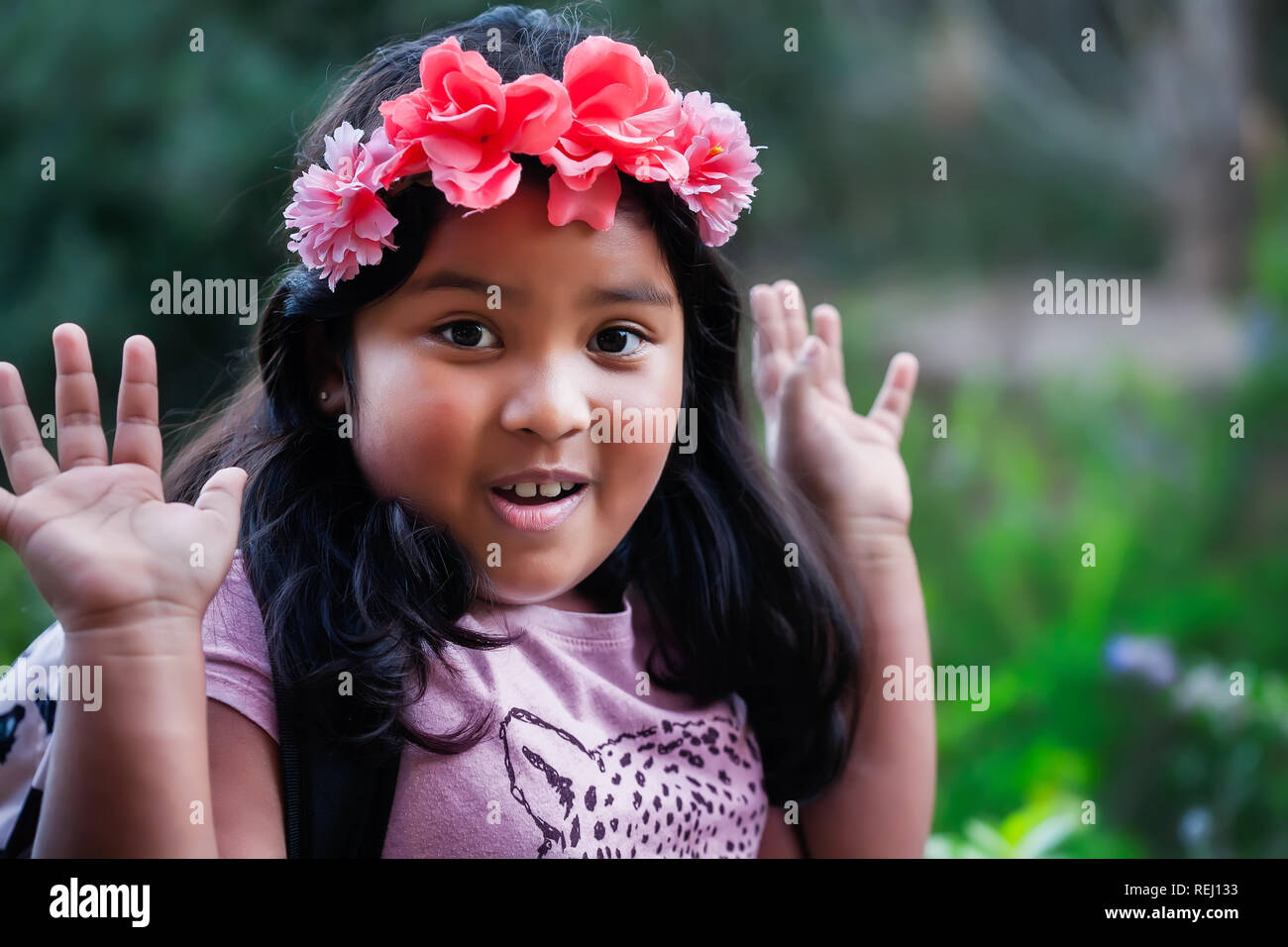 Un bel giovane nativo cerca ragazza indossando uno zaino e floreali come la fascia di testa con le mani in aria, esprimere un emozione di sorpresa. Foto Stock