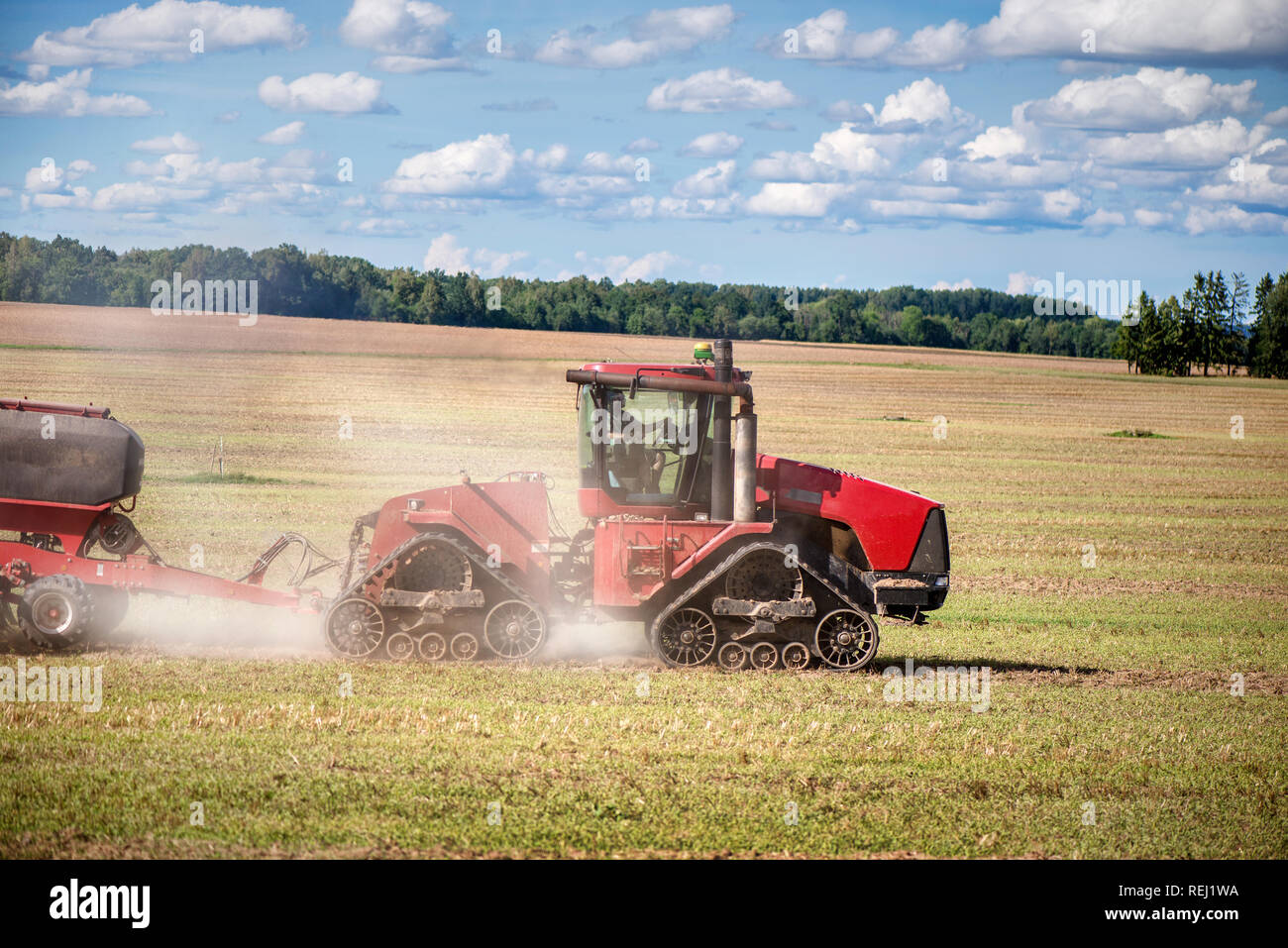 Sfondo agricoli con red tractor pulling aratro, gettando polvere nell'aria. Mietitrebbia al campo di grano. Macchinari pesanti durante la coltivazione, wor Foto Stock