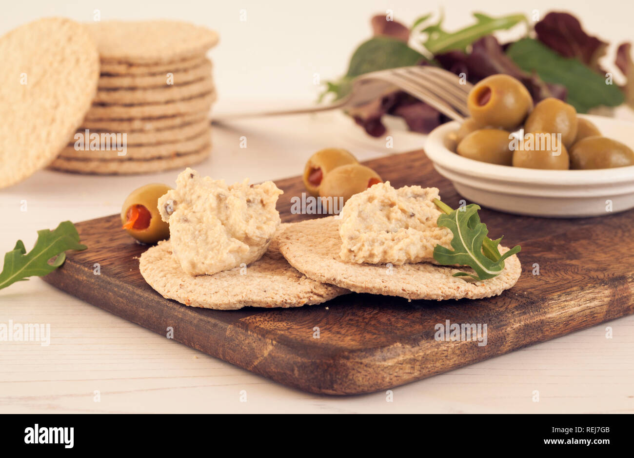 Senza glutine oatcakes con hummus e olive verdi e insalata su pannello di legno Foto Stock