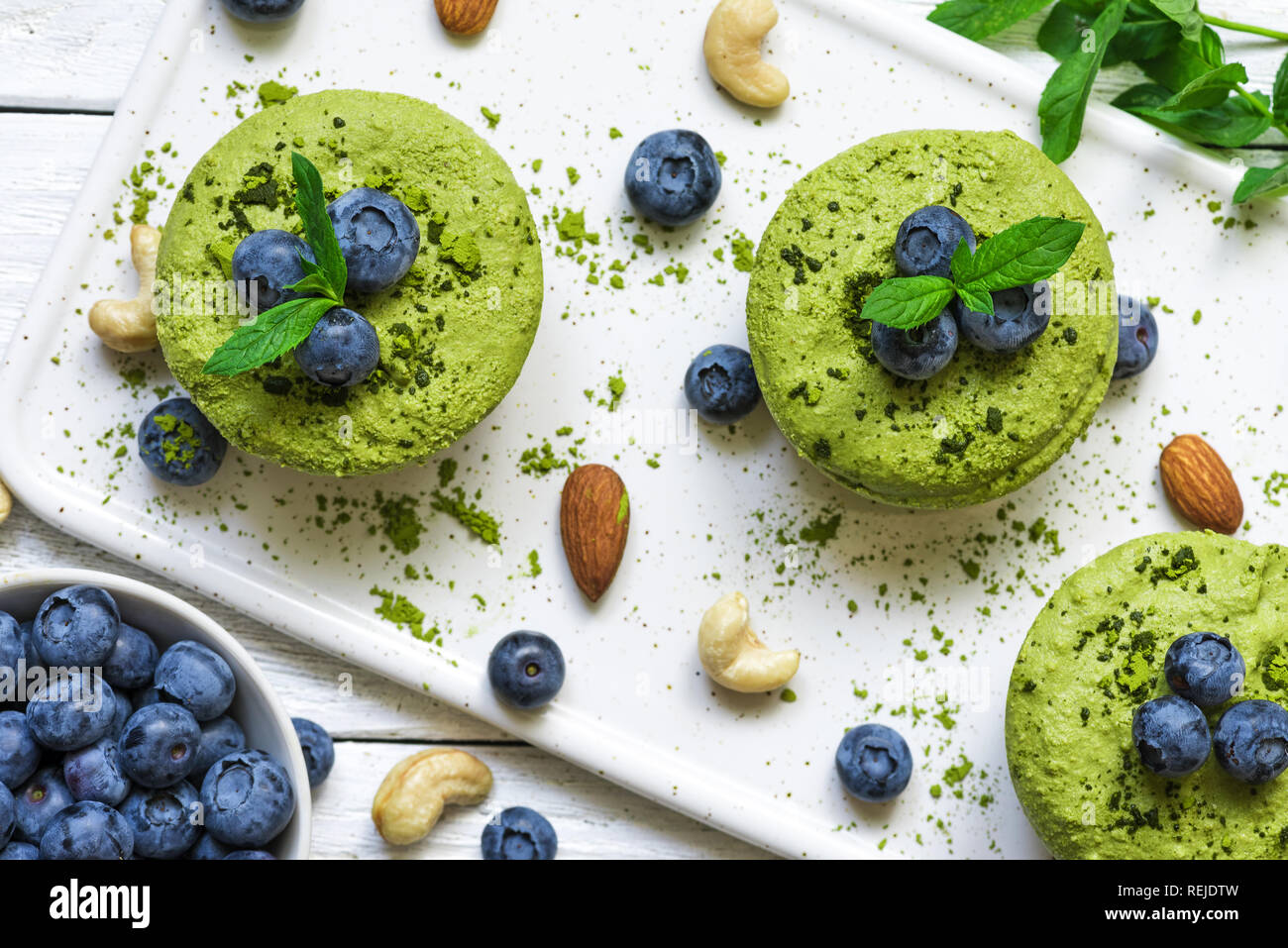 In casa materie matcha polvere torte con frutti di bosco freschi, menta, dadi. sano cibo vegan concetto. vista superiore Foto Stock