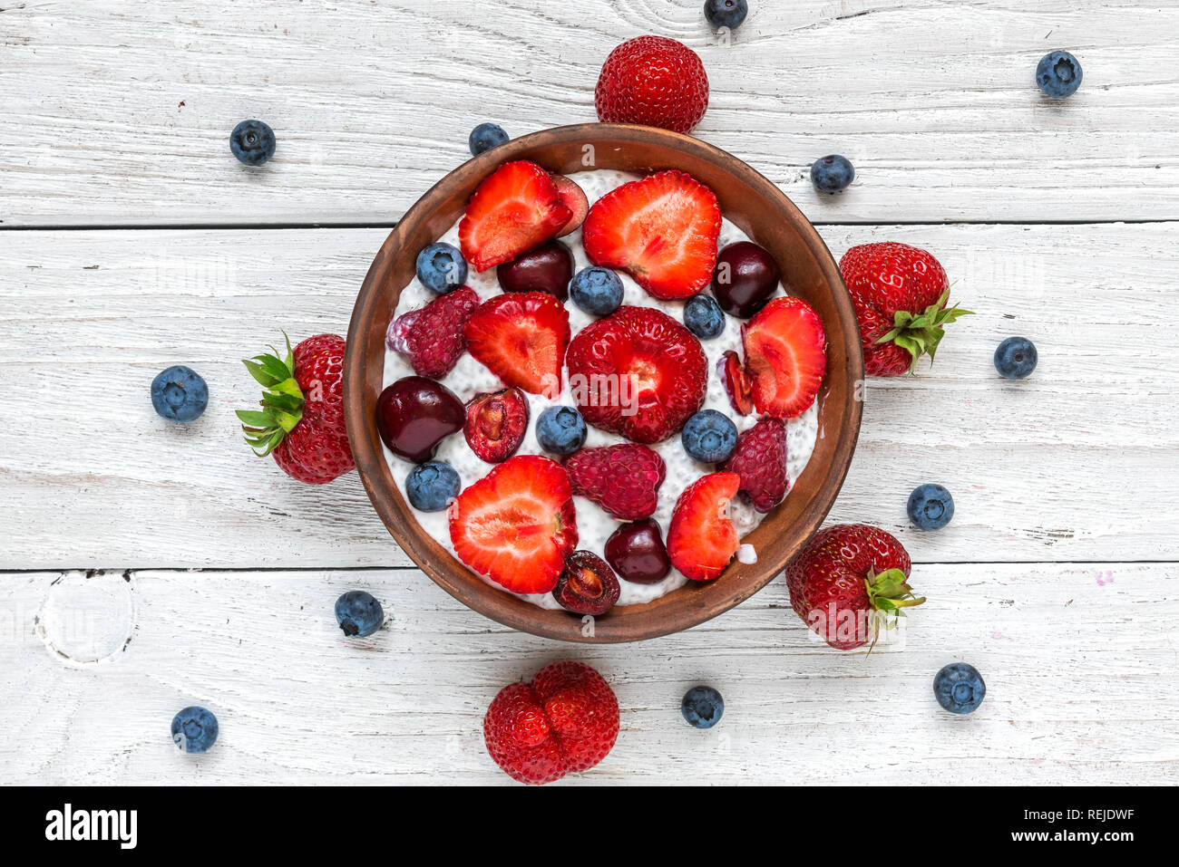 In casa berry yogurt o budino di Chia con fresche lamponi, fragole, ciliegie e mirtilli in una ciotola. Colazione sana. vista superiore Foto Stock In casa berry yogurt o budino di Chia con fresche lamponi, fragole, ciliegie e mirtilli in una ciotola. Colazione sana. vista superiore Foto Stock