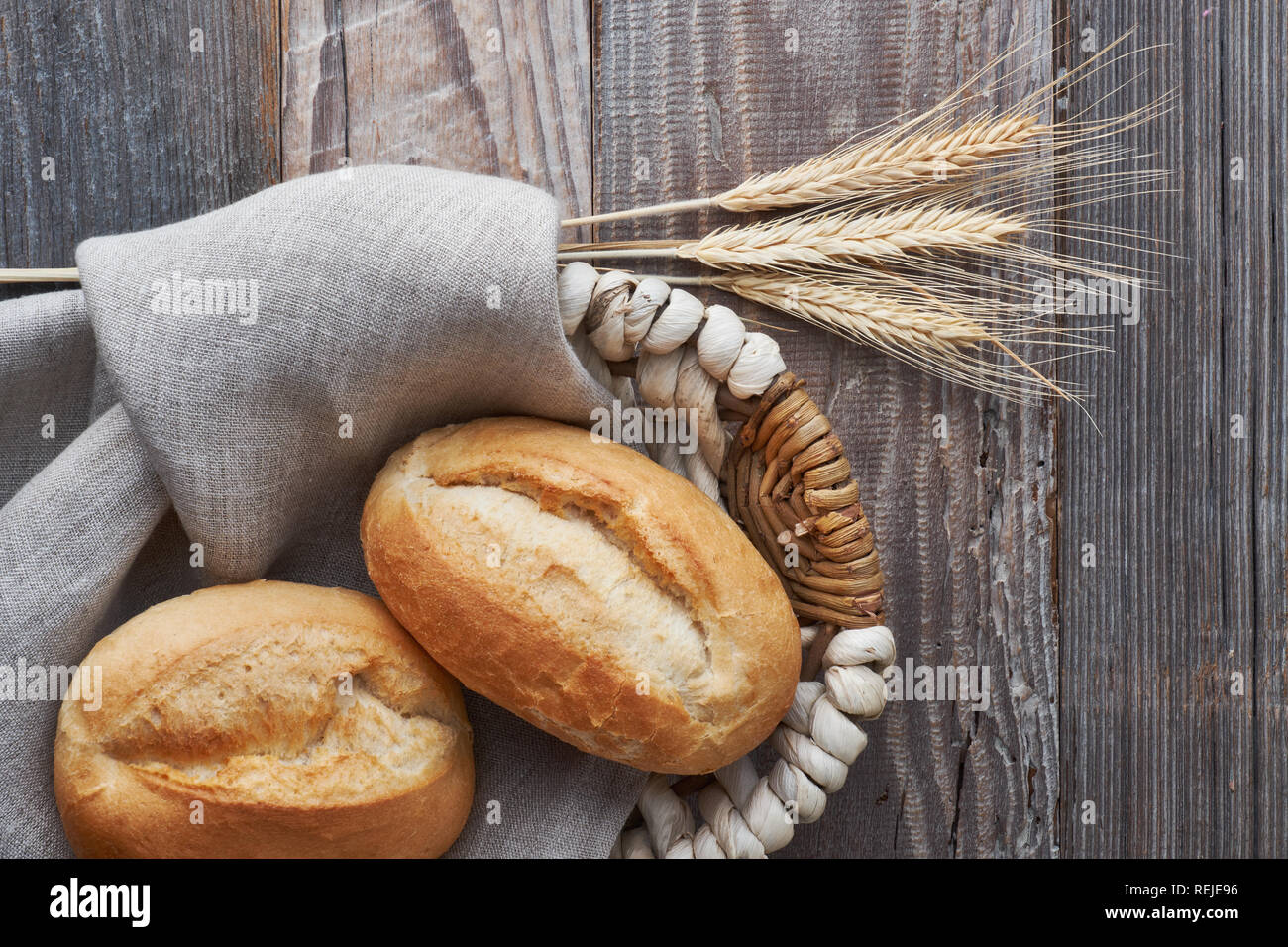Ciambelle di pane in un cestino di legno rustico con spighe di grano, vista dall'alto Foto Stock