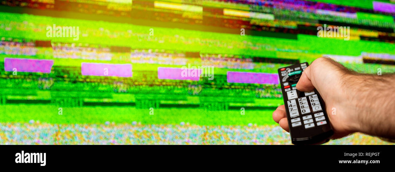 Uomo con grande tv remote cercando di fissare la televisione digitale di un rumore su un grande plasma display OLED 4K Ultra HD High Dynamic Range HDR Smart TV flare Foto Stock