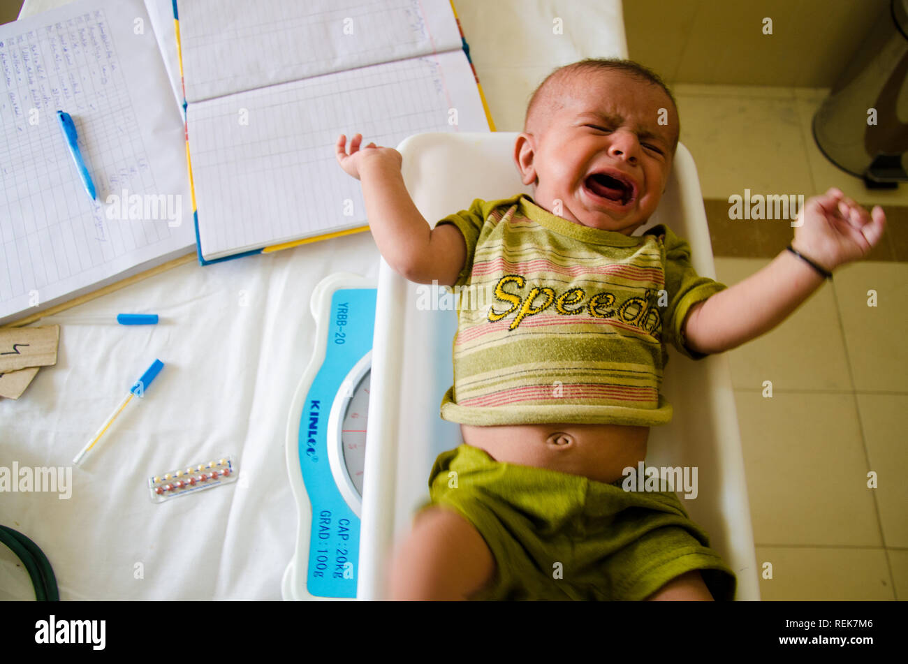 Un bambino viene pesato in un primario salute facility in Pakistan. Foto Stock