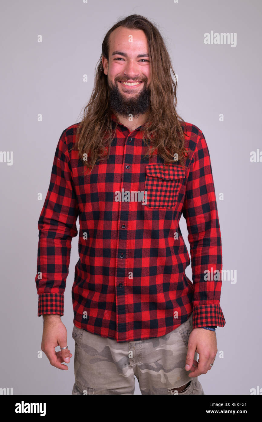 Ritratto di giovane felice barbuto hipster uomo con capelli lunghi sorridente Foto Stock