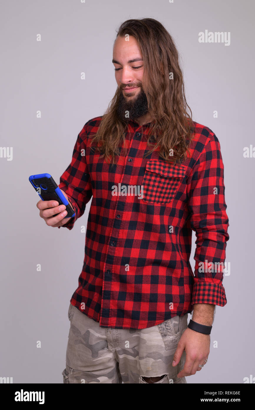 Ritratto di giovane felice barbuto hipster uomo usando il telefono Foto Stock