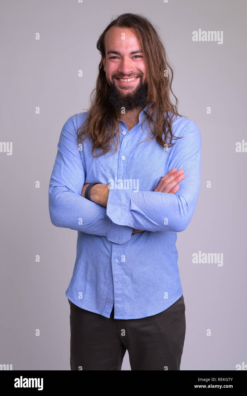 Ritratto di giovane happy businessman barbuto sorridente con le braccia incrociate Foto Stock