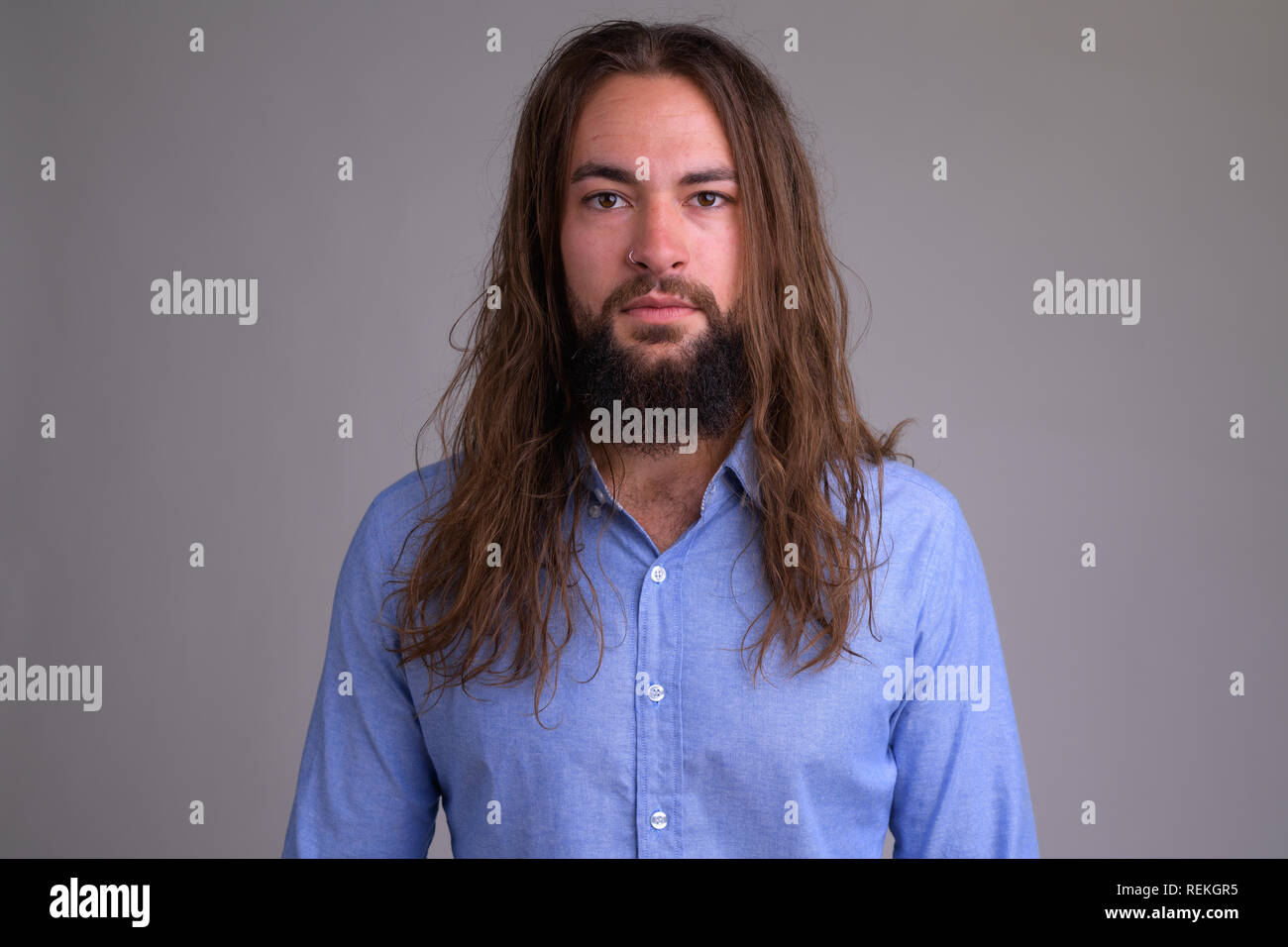 Ritratto di giovane bello barbuto imprenditore con capelli lunghi Foto Stock