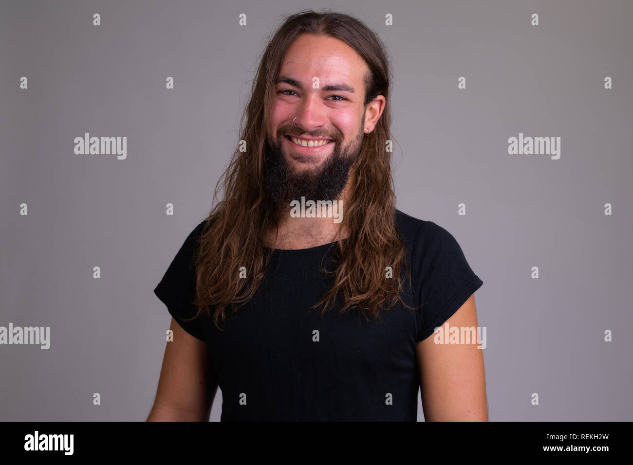 Felice giovane uomo barbuto con i capelli lunghi sorridente Foto Stock
