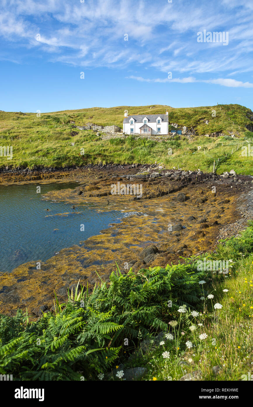 Vista di un tradizionale cottage sul mare con la bassa marea su una bella giornata estiva, Isle of Scalpay, Ebridi Esterne, Scotland, Regno Unito Foto Stock