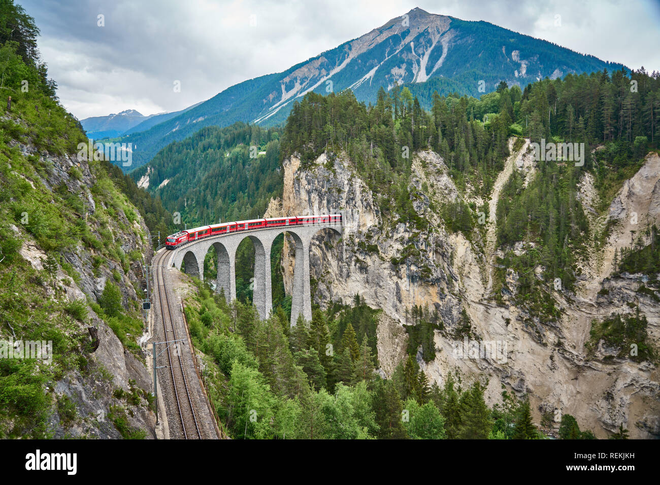 Il treno rosso passa sopra il ponte Landwasser Viaduct, nel cantone di Graubünden, Svizzera. Bernina Express / Glacier Express utilizza questa ferrovia. Foto Stock