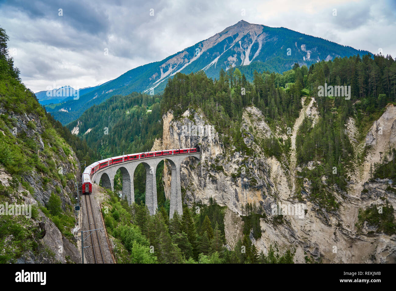 Il treno rosso passa sopra il ponte Landwasser Viaduct, nel cantone di Graubünden, Svizzera. Bernina Express / Glacier Express utilizza questa ferrovia. Foto Stock