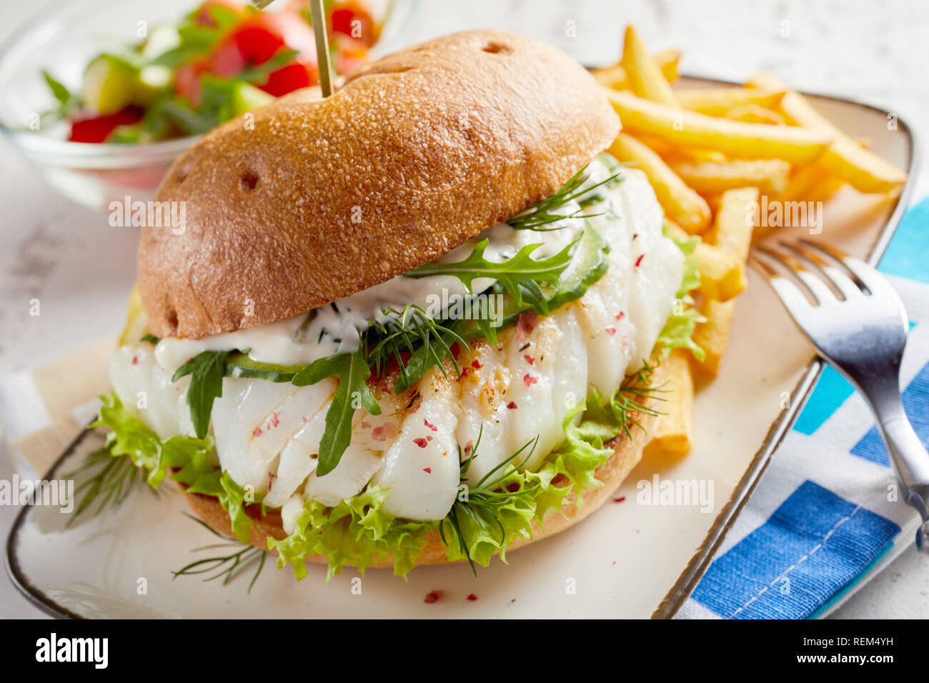 Pesce Gourmet hamburger di pesce con mayo e insalate fresche e erbe su una  focaccia croccante con il lato che serve di patatine Foto stock - Alamy