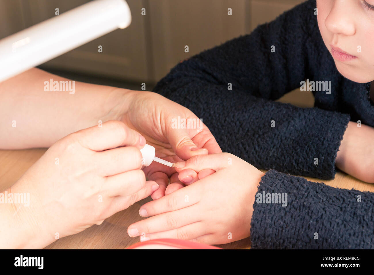 Close up di mani giovani ragazze mano mentre l'applicazione di smalto trasparente polacco, processo di manicure e la cura delle unghie Foto Stock