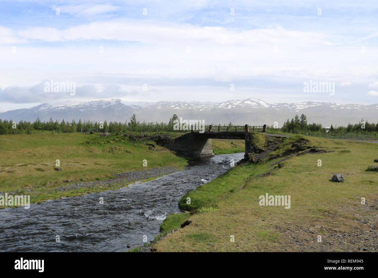 Brücke über Fluss mit Schnee und Bergen im Hintergrund in isola Foto Stock