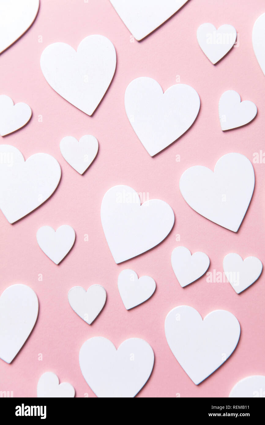 Cuori di colore bianco su un pastello sfondo rosa. Foto Stock