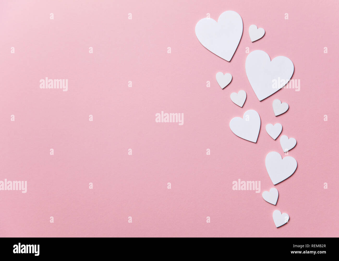 Cuori di colore bianco su un pastello sfondo rosa. Foto Stock