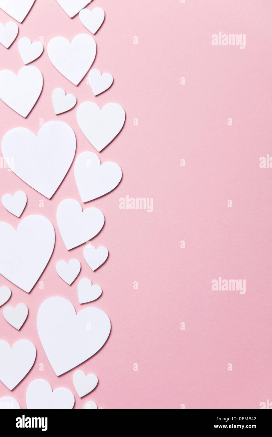 Cuori di colore bianco su un pastello sfondo rosa. Foto Stock