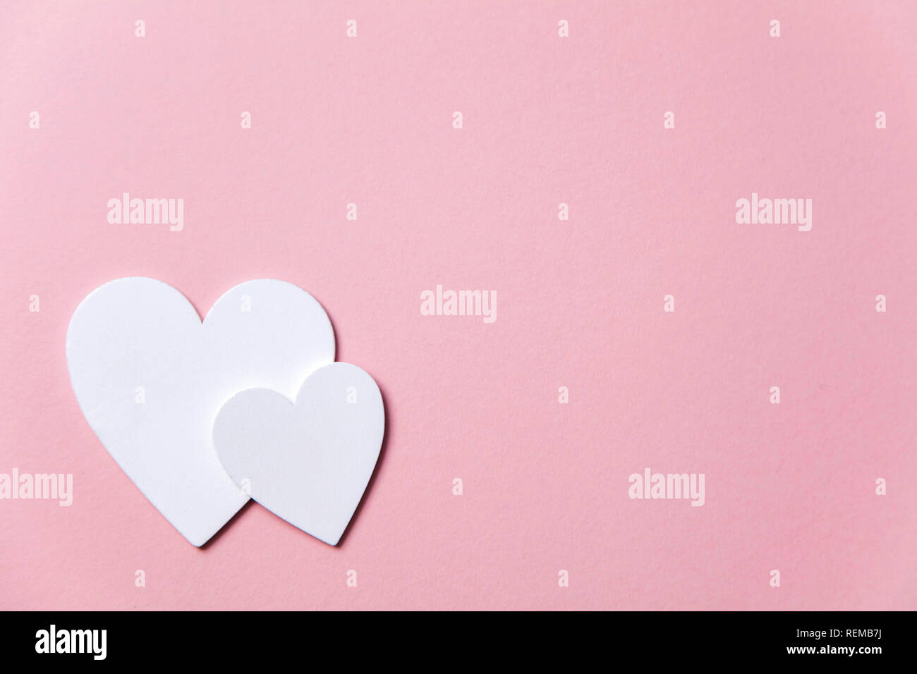 Cuori di colore bianco su un pastello sfondo rosa. Foto Stock