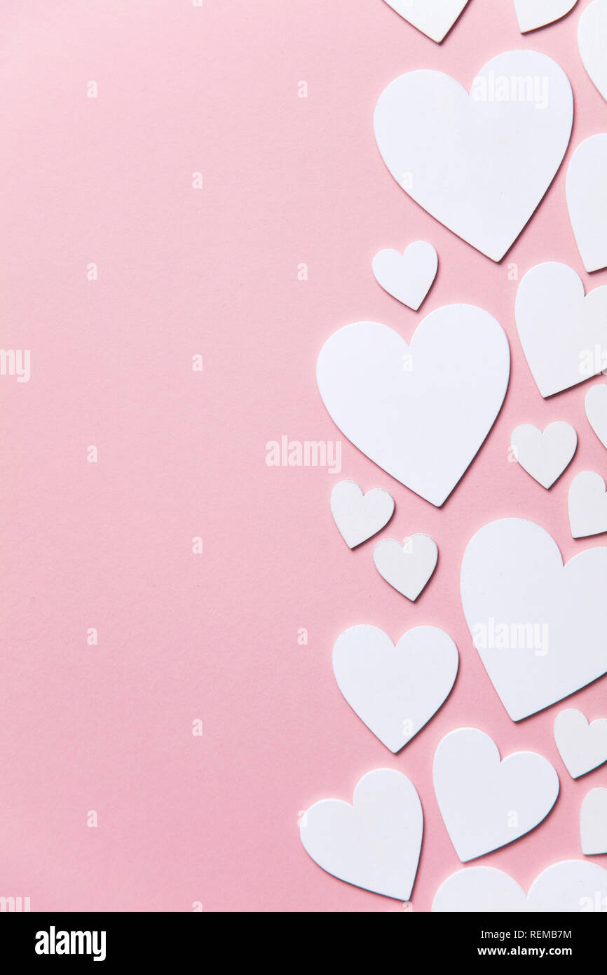 Cuori di colore bianco su un pastello sfondo rosa. Foto Stock