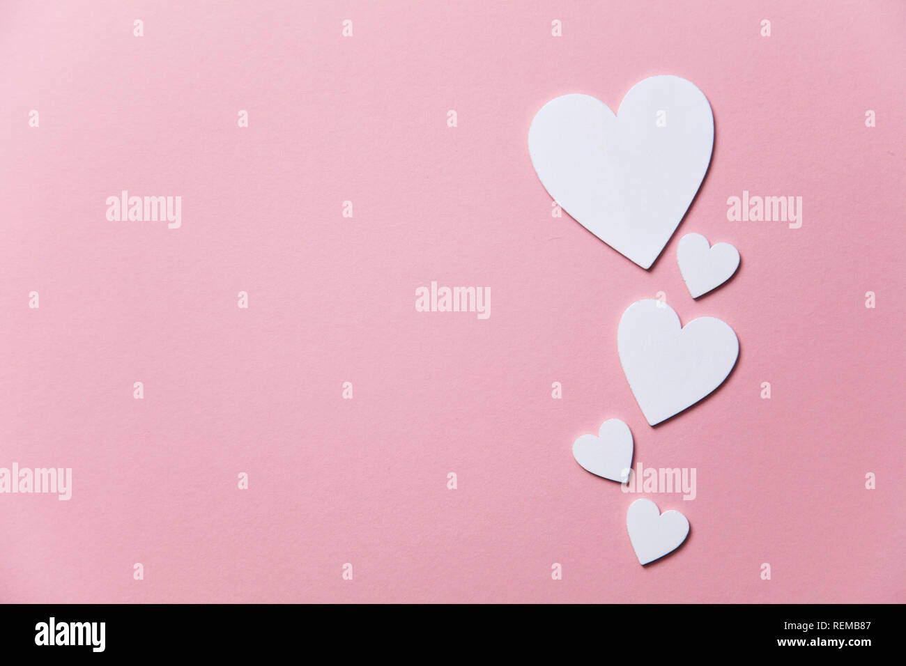 Cuori di colore bianco su un pastello sfondo rosa. Foto Stock