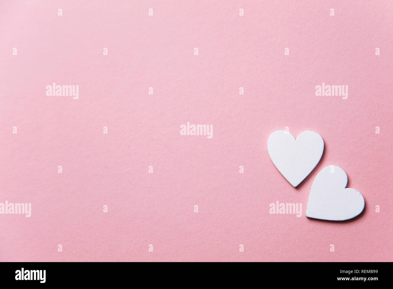 Cuori di colore bianco su un pastello sfondo rosa. Foto Stock