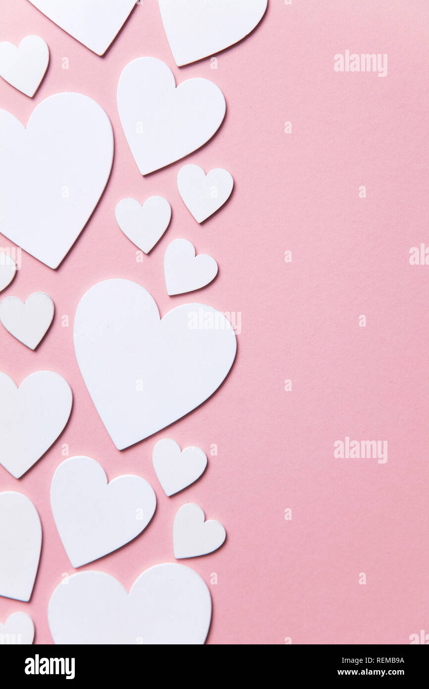 Cuori di colore bianco su un pastello sfondo rosa. Foto Stock