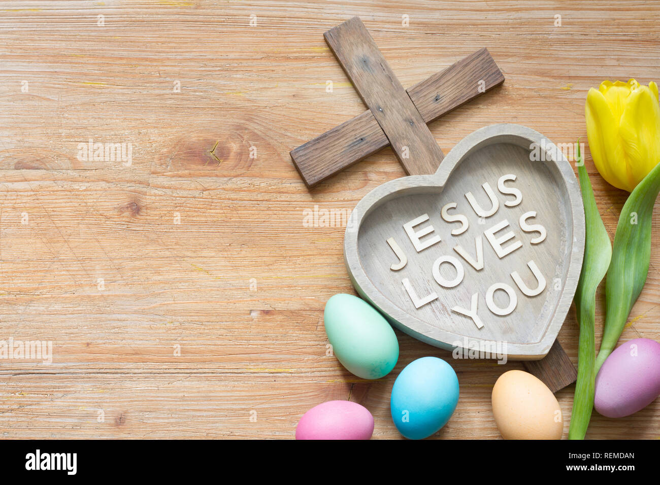 Croce di Pasqua e di cuore con iscrizione Gesù vi ama in legno astratto bordo della molla Foto Stock