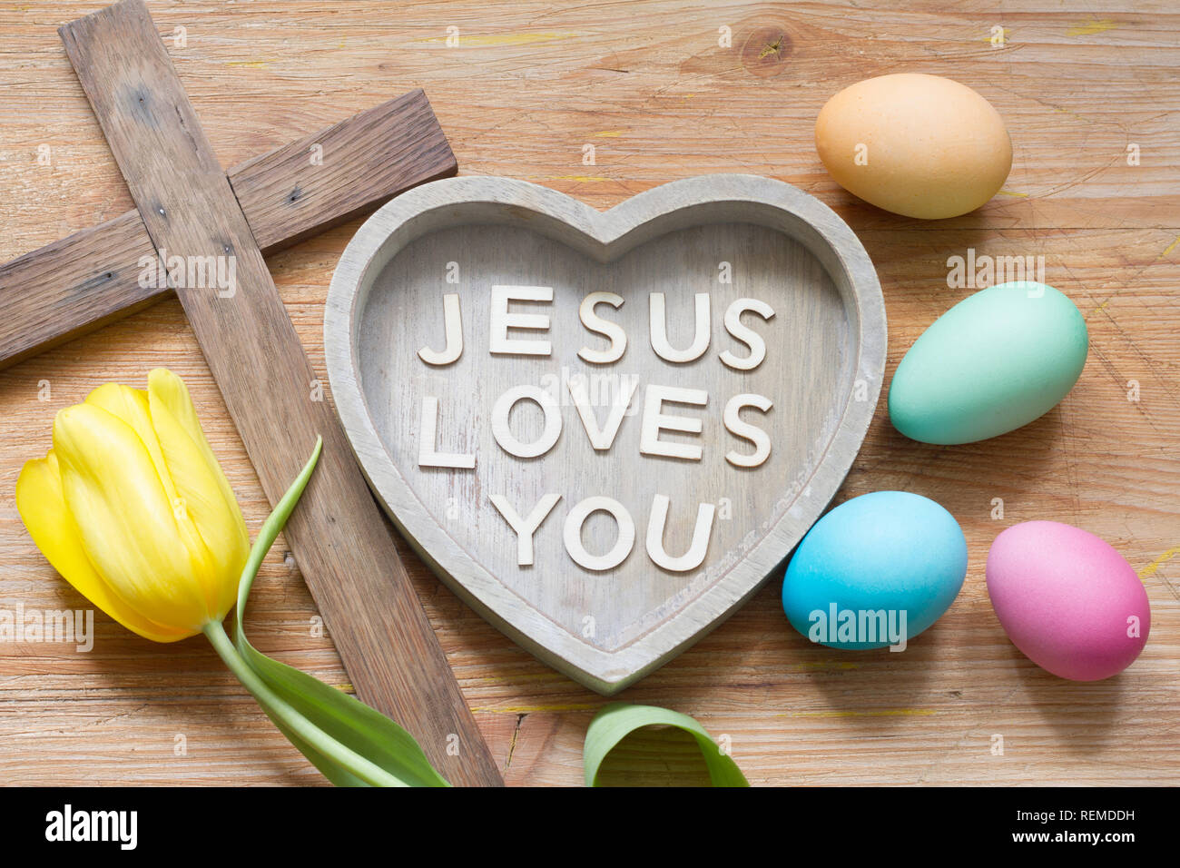 Croce di Pasqua e di cuore con iscrizione Gesù vi ama in legno astratto bordo della molla Foto Stock