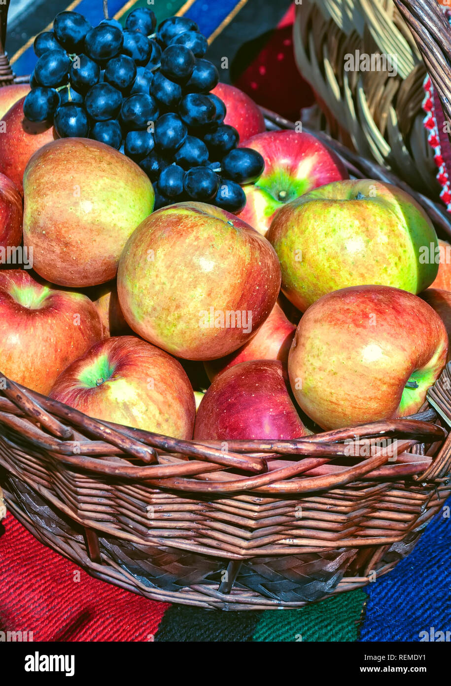 Un cesto pieno di mele e uva; Foto Stock