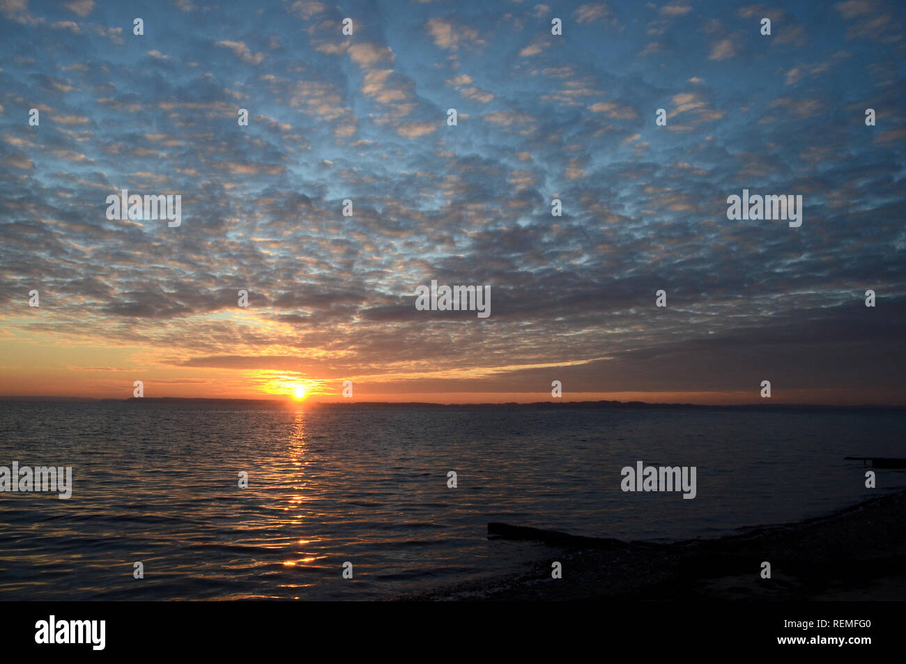 Paesaggio con tramonto e altocumulus nuvole sopra il mare. Foto Stock