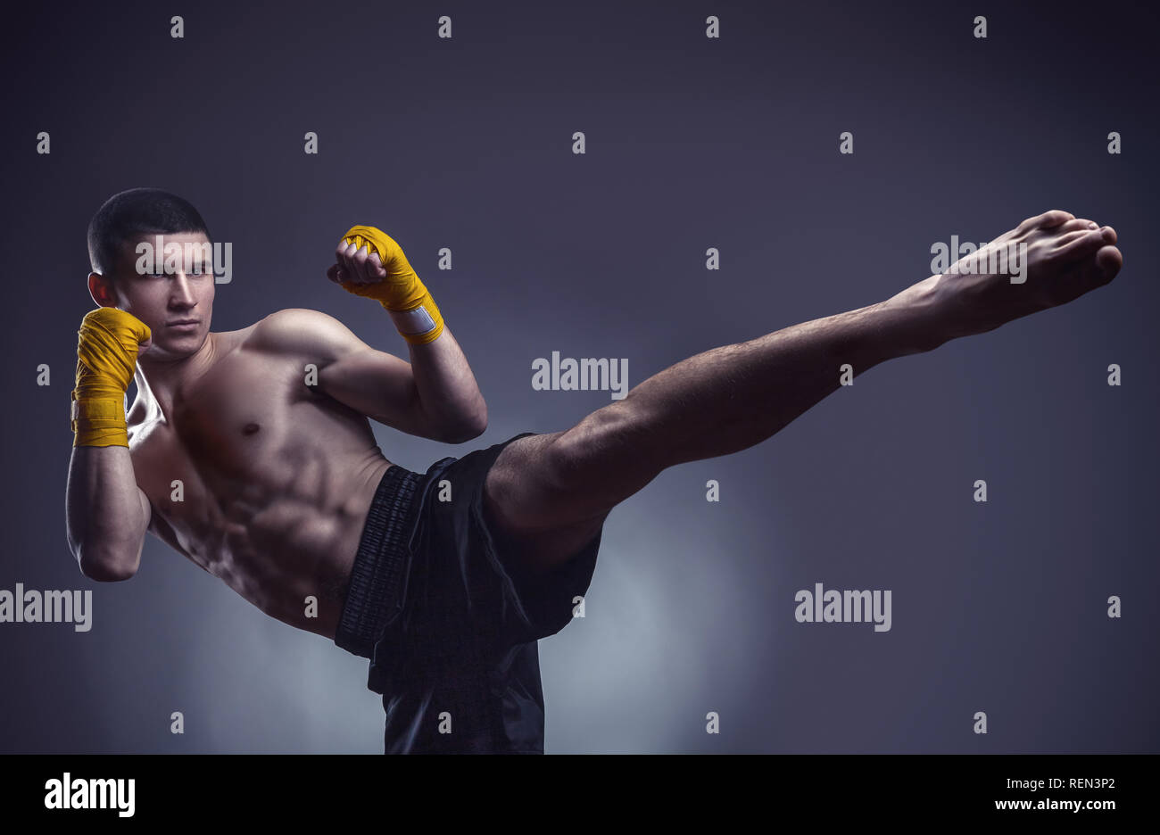 Muay Thai kickboxer o esecuzione di un potente calcio contro lo sfondo nero Foto Stock